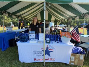 Women standing behind table at event under a tent
